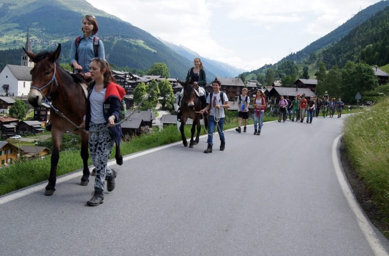Klasse zieht mit Saumtieren durch ein Bergdorf