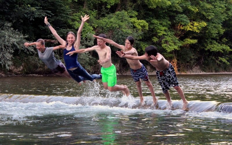 Jugendliche springen im Klassenlager gemeinsam in den Fluss