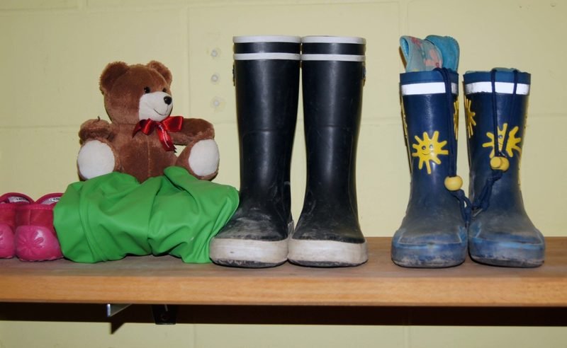 Stoffbär und Gummistiefel auf der Bank in der Garderobe